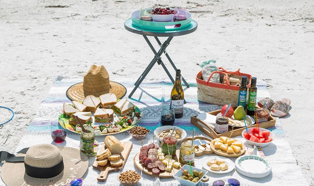 Article Cards Featured Image Picnic on the beach featuring products from Harry & David, sandwiches, fruits, charcuterie boards, wine, relish, crackers