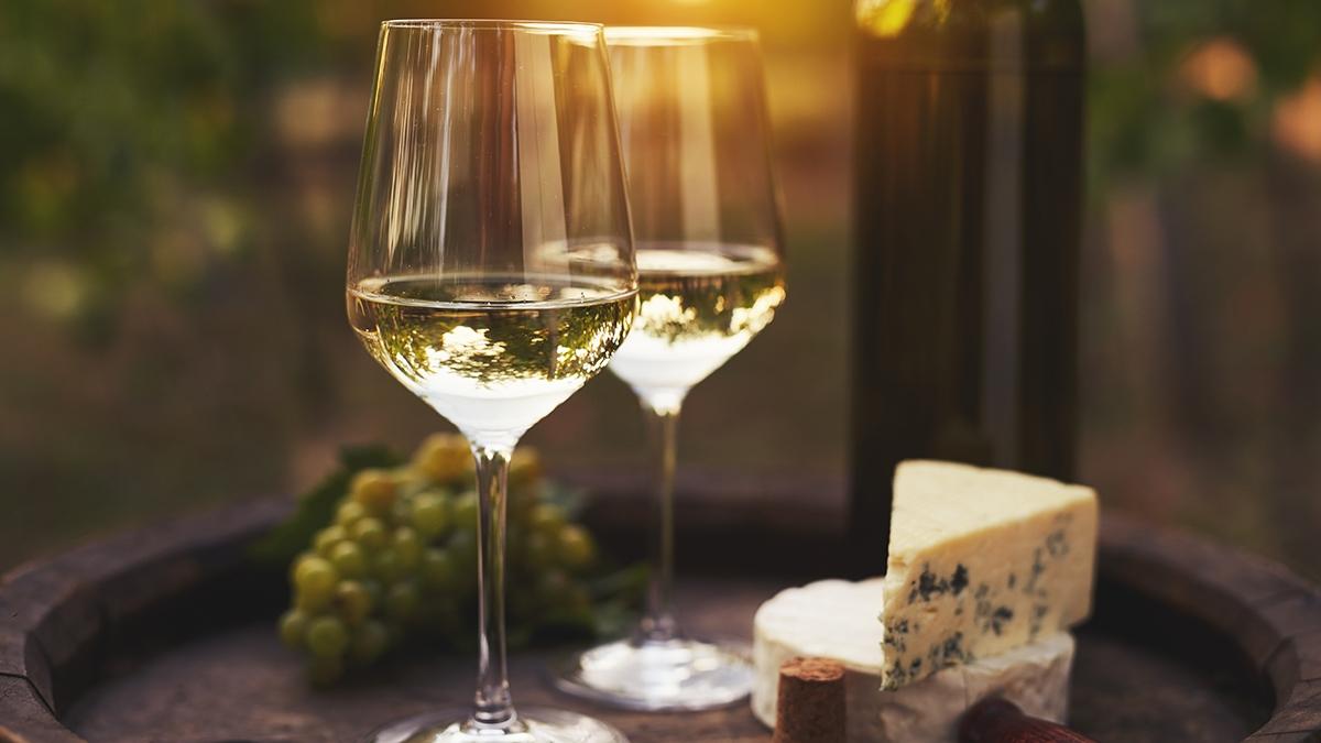 Article Cards Featured Image Two glasses of white wine on the old wooden barrel outdoors. Sun