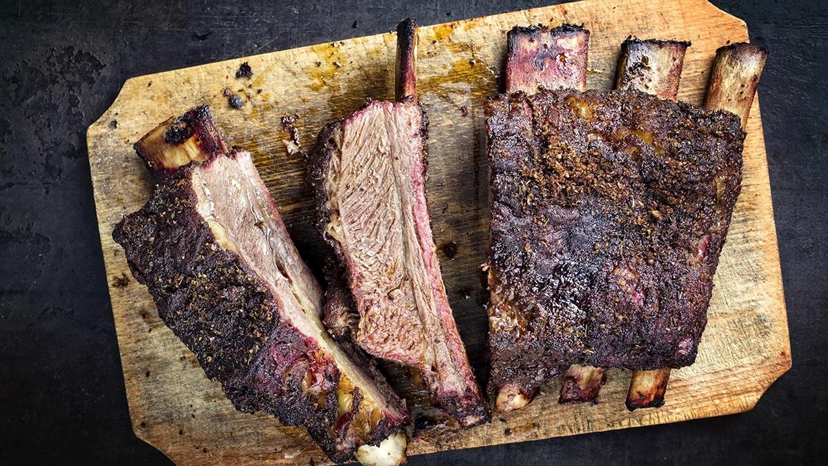 Barbecue chuck beef ribs with hot rub as top view sliced on a wooden cutting board