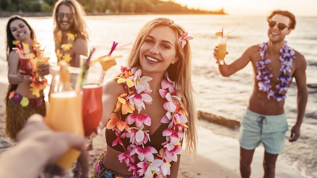 summer birthday with group of young friends drinking cocktails on beach