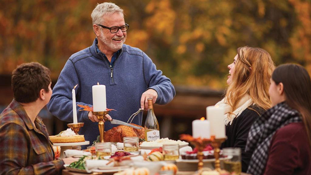 This is an image of Thanksgiving quotes. Family eating Thanksgiving dinner outdoors.