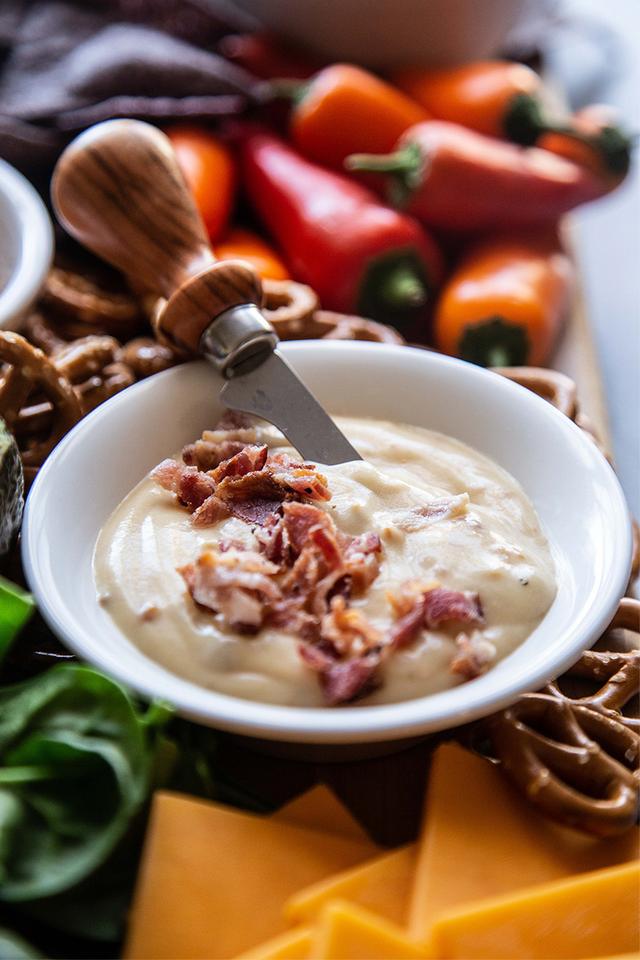 Snack board with a bowl of bacon beer cheese dip.