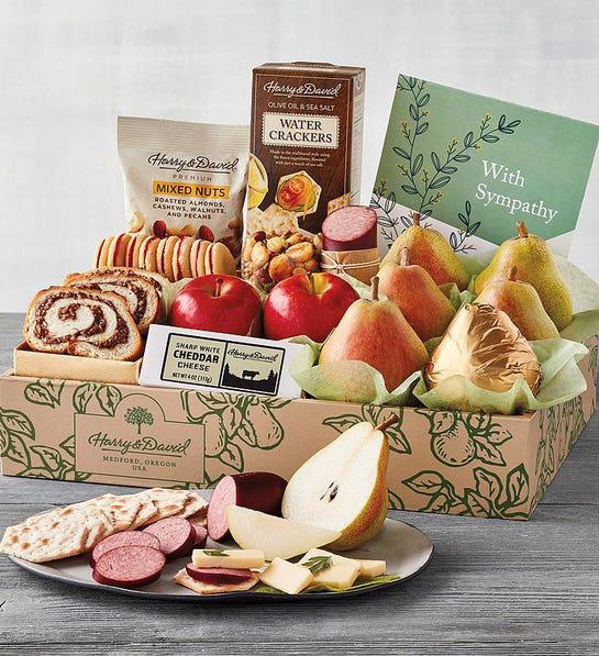 Sympathy gift ideas image   Harry & David Deluxe Sympathy Gift Box with sliced pear, sausage, cheese and crackers on a plate in front of the box.