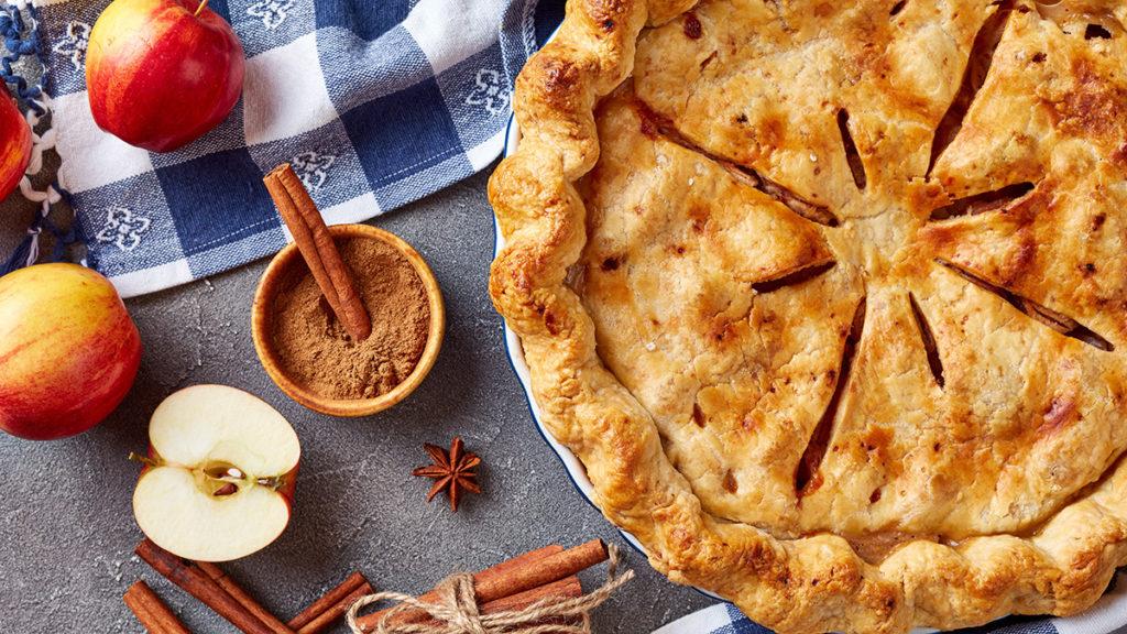 Apple image   overhead view of Freshly baked delicious classic homemade American apple pie on a concrete table with kitchen towel and ingredients, view from above, close up, macro