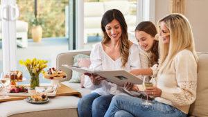 A photo of mother's day quiz with two mothers and their daughter looking at a photo album