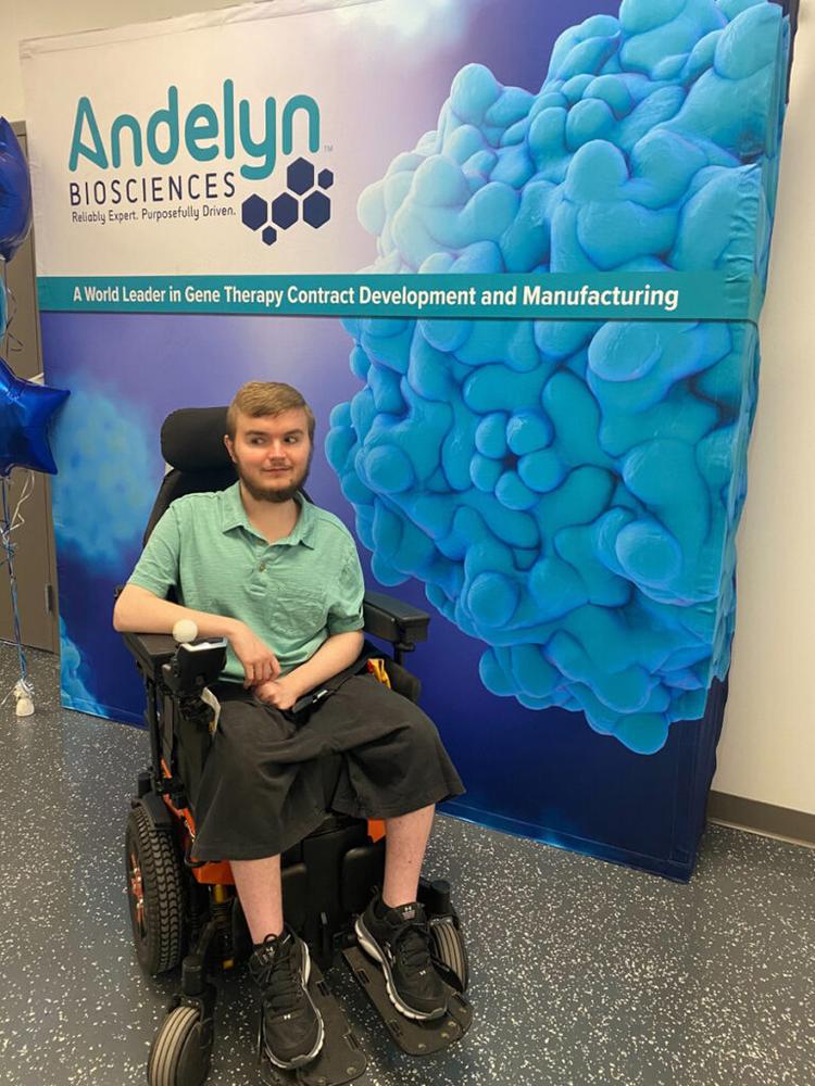 Caregiver with a young man in a wheelchair at a medical conference.