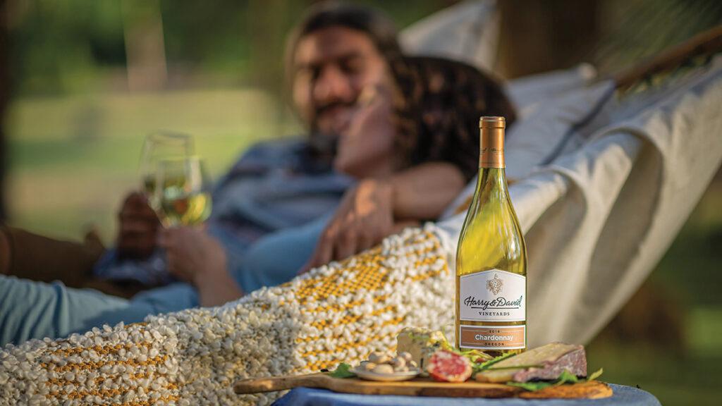 Chardonnay bottle next to a couple in a hammock.